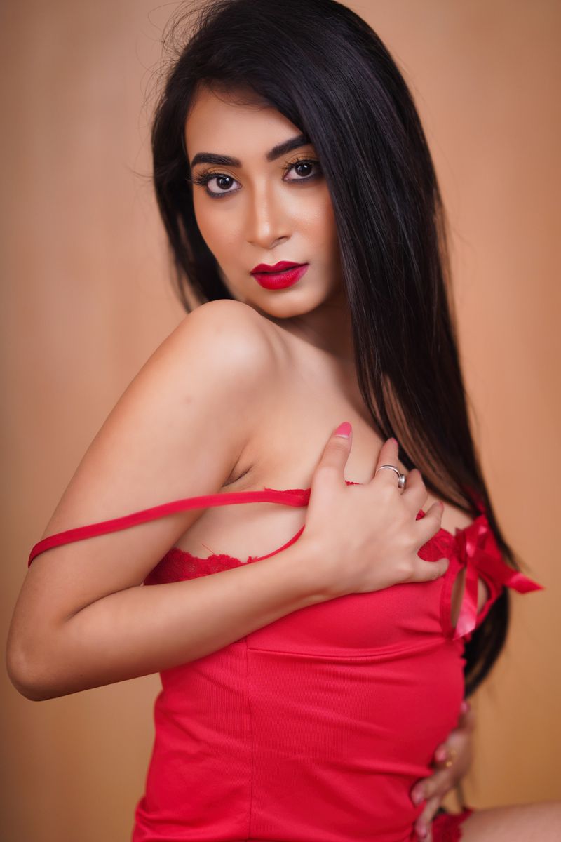 Sensual portrait of an adult woman posing in red lingerie with alluring red lips.
