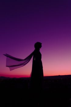 Silhouette of a woman standing against a vibrant sunset sky in Kayseri, Türkiye.