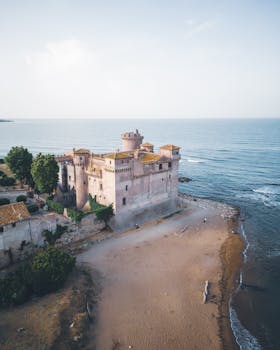 Drone shot of Santa Severa Castle on the Italian coastline with sandy beach and blue sea.