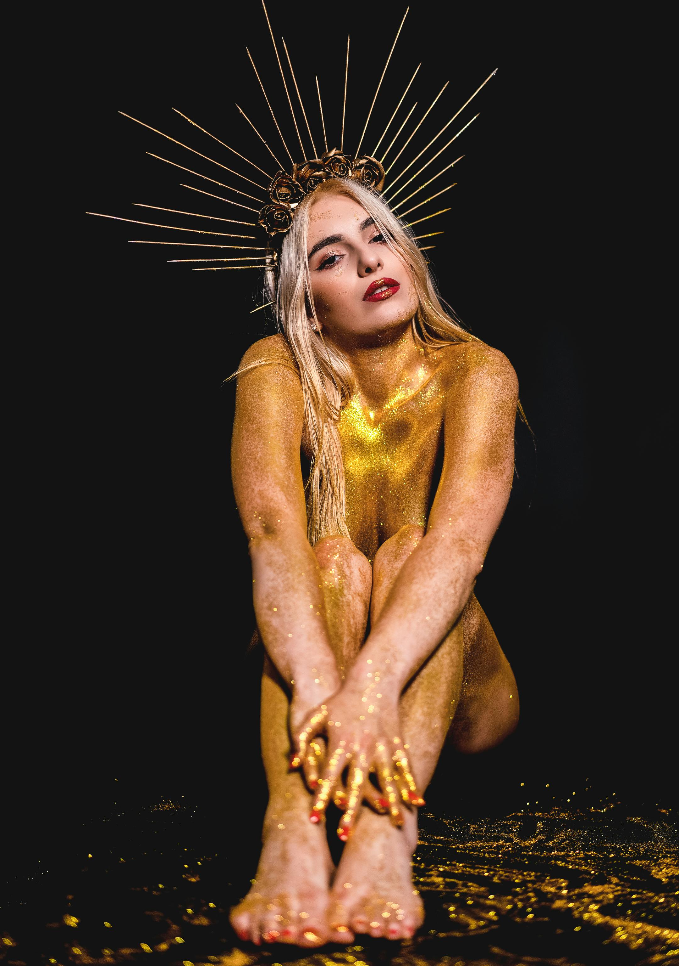 studio portrait of a naked blonde covered in gold glitter