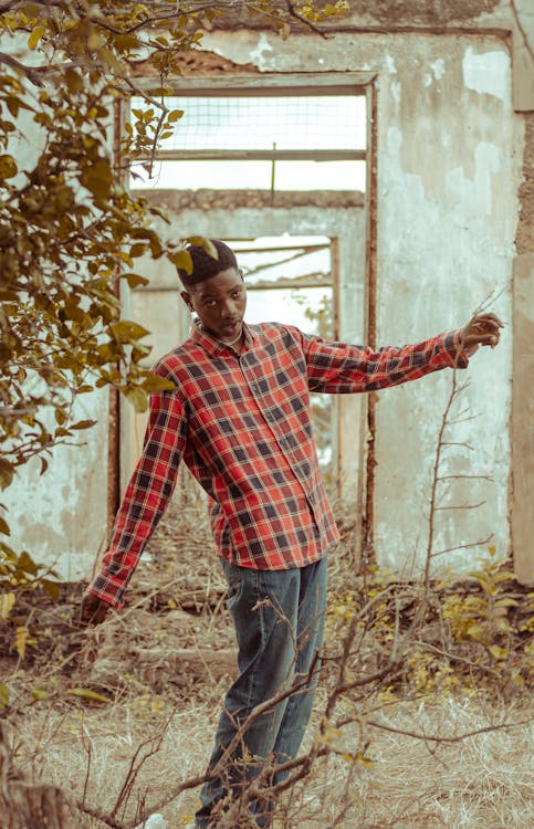 Man in Red and Blue Checkered Long Sleeve Shirt and Denim Pants Posing Near the Plants