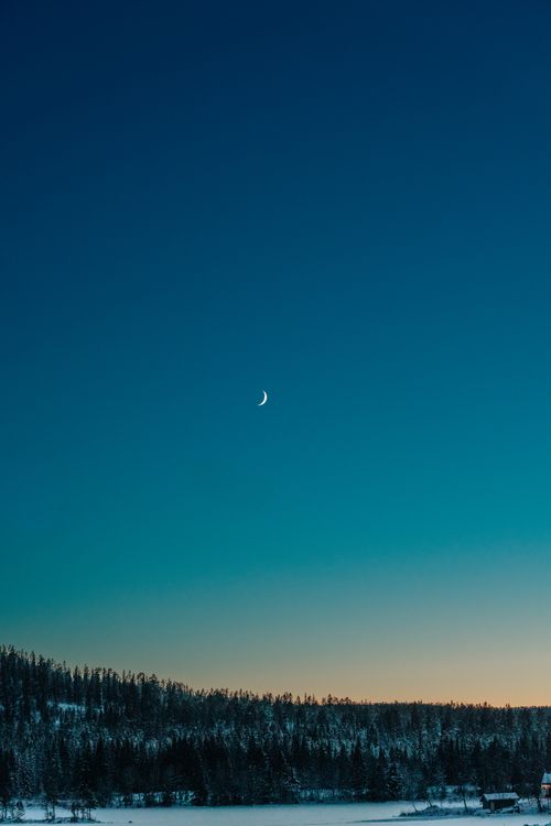 Free Serene winter landscape in Norway showcasing a crescent moon over snowy hills at dusk. Stock Photo