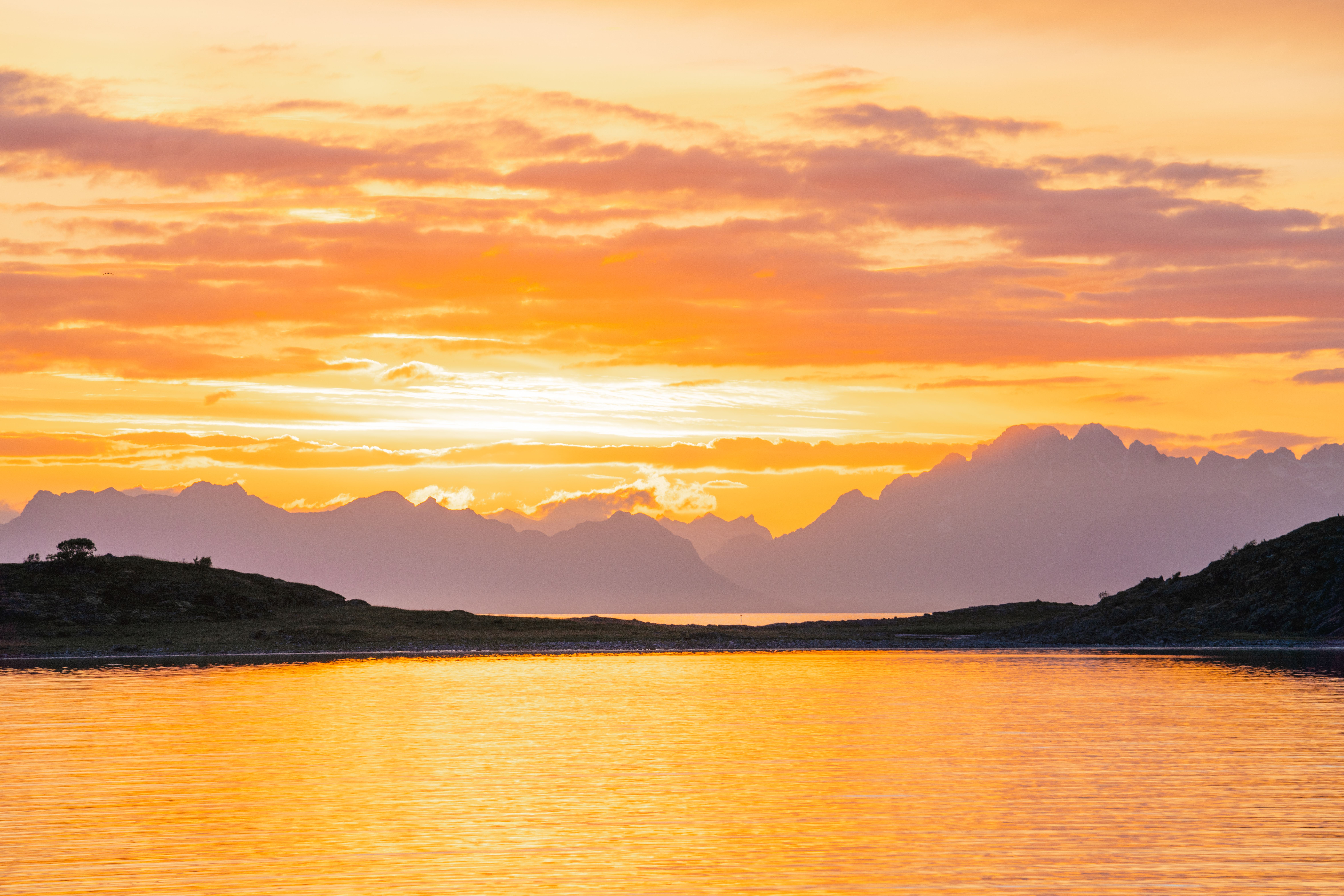 Stunning sunset view over a fjord in Nordland, Norway with mountain silhouette.