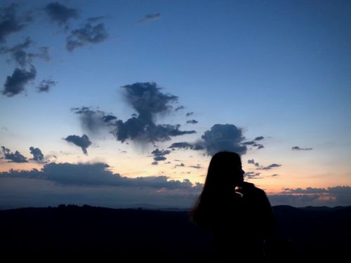 Free A scenic silhouette of a woman against a vibrant sunset sky, evoking serenity and reflection. Stock Photo