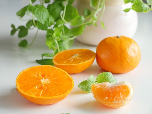 Бесплатное стоковое фото с апельсиновые дольки, апельсины, белая поверхность