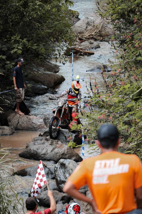 Free Motocross rider skillfully maneuvers through a rocky creek in Bandung, showcasing thrilling enduro racing. Stock Photo