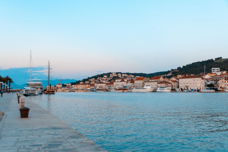 Picturesque harbor in Trogir, Croatia with boats and historic buildings at sunset.