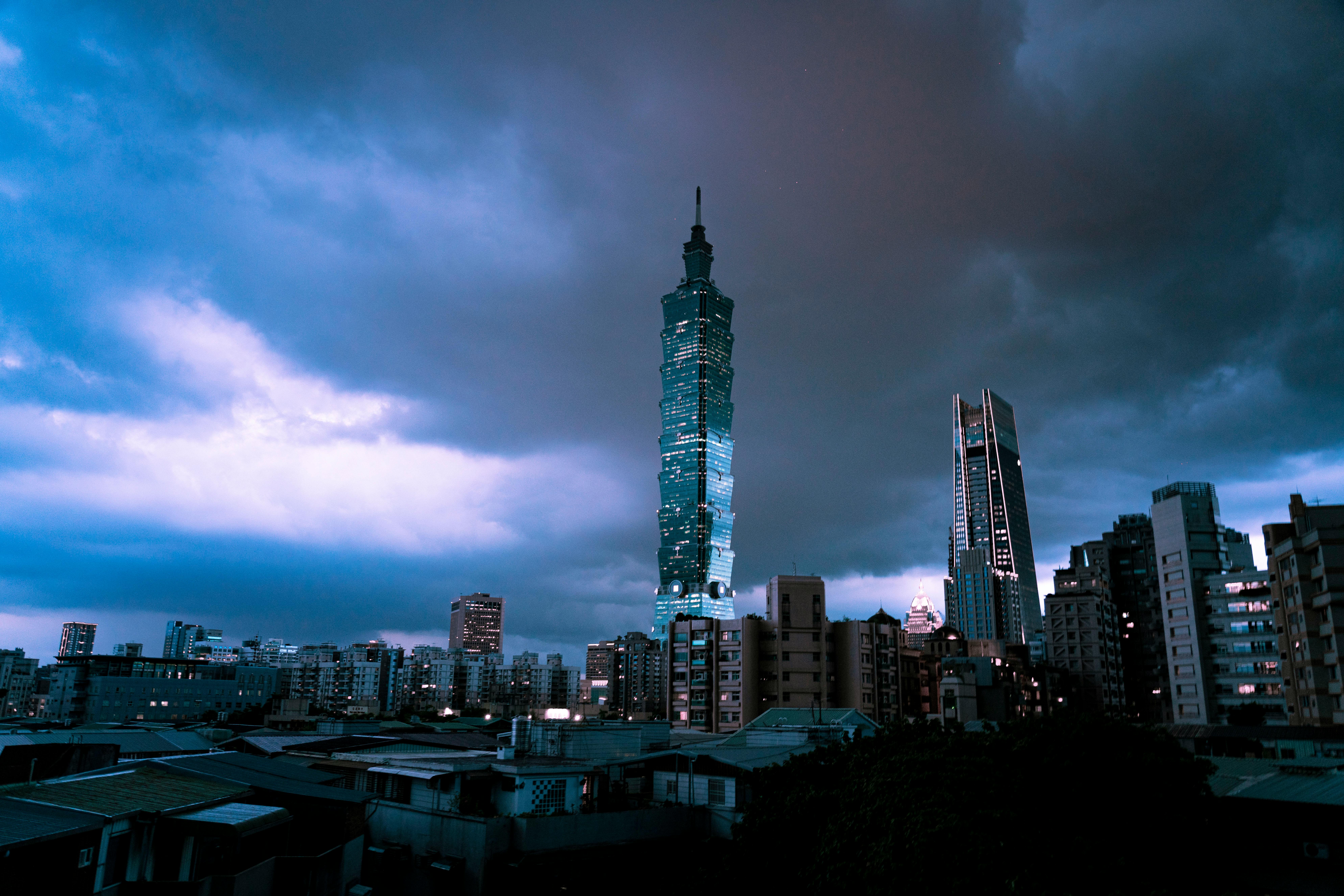 Dramatic twilight cityscape featuring Taipei 101 amidst urban skyline and stormy clouds.