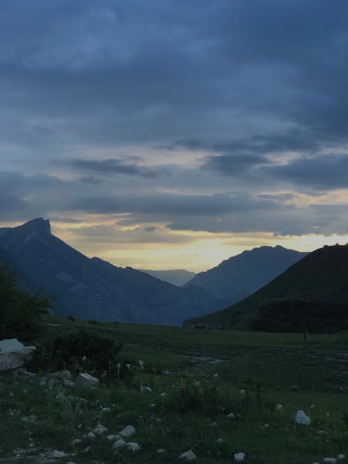 Mountain Ranges Under a Cloudy Sky at Sunset