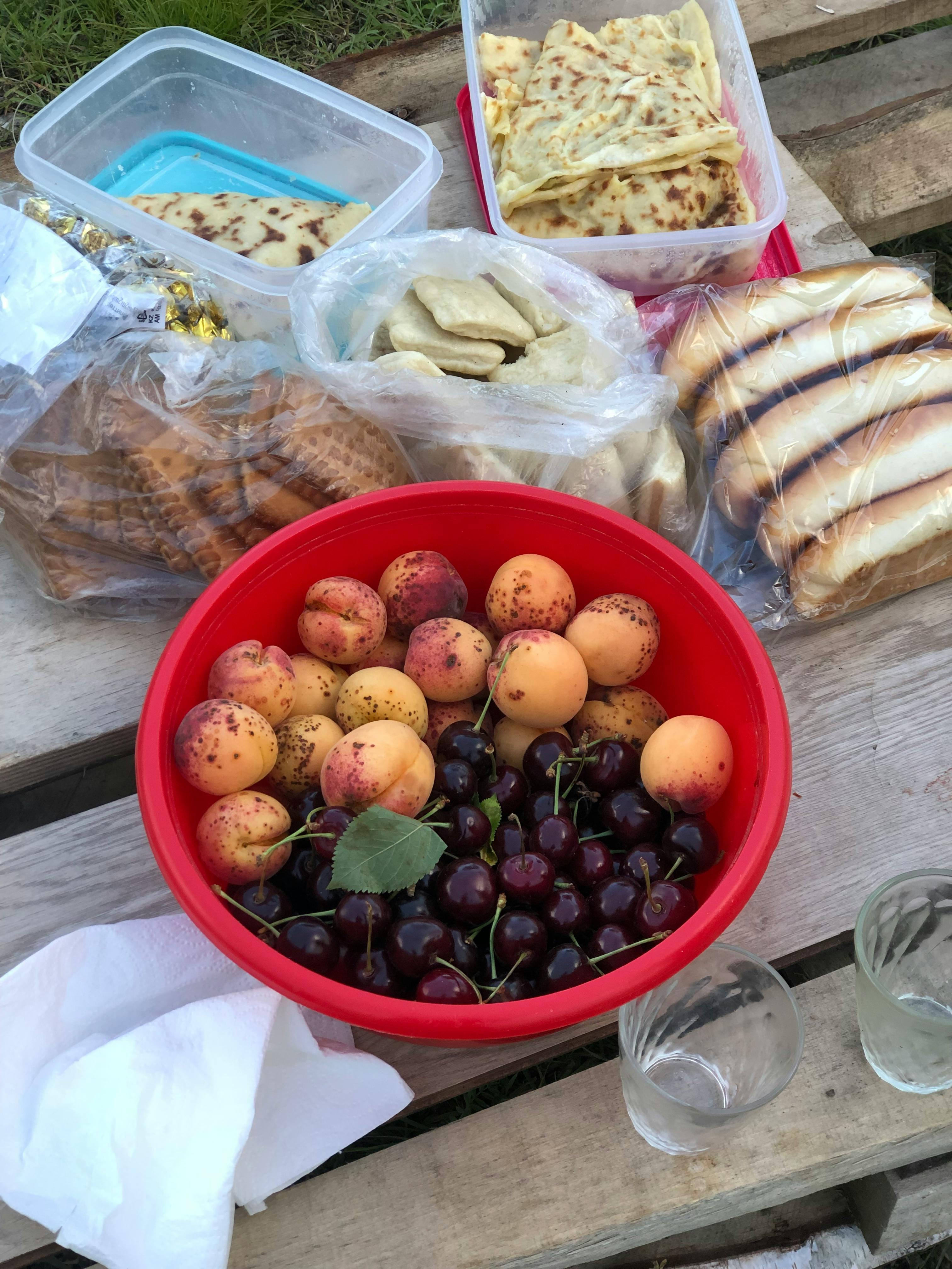 A vibrant picnic setup features fresh apricots, cherries, and an assortment of breads in Кегер, Russia.