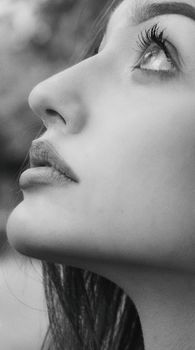 Minimalist close-up black-and-white portrait of a woman looking upwards, conveying elegance and thoughtfulness.
