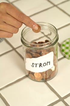 Hand placing a coin into a savings jar labeled 'Strom', symbolizing financial planning and savings.