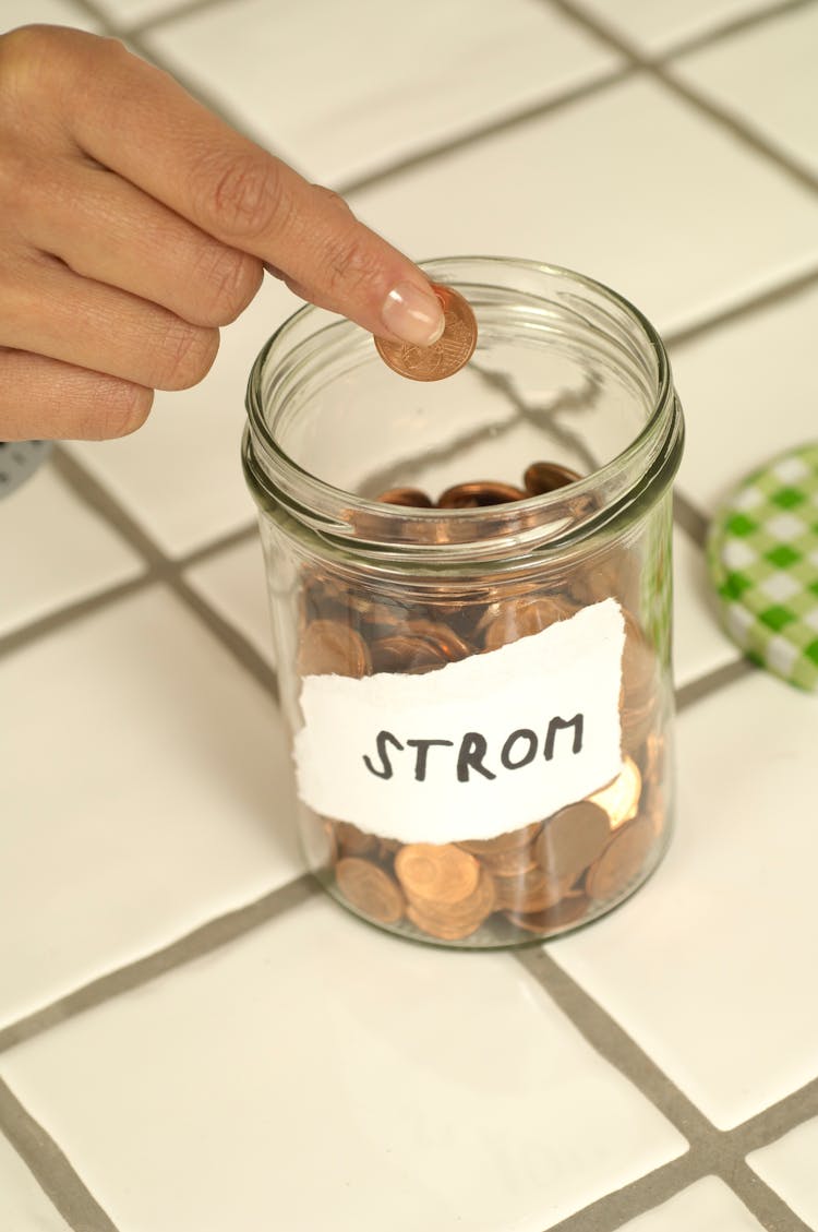 Hand Putting Coins Into Jar