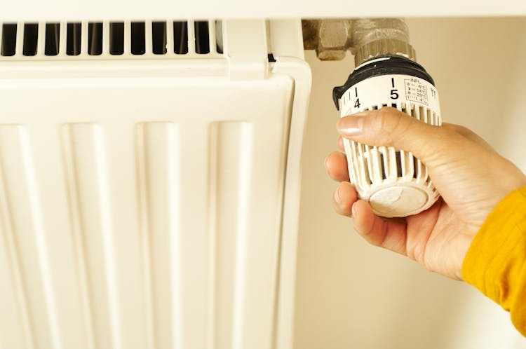 Hand Of A Person Turning The Radiator Valve