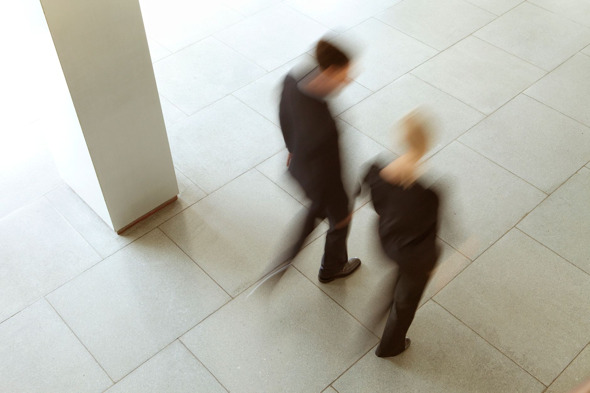 Artistic blurred photograph of two people walking in an urban environment, capturing dynamic motion.