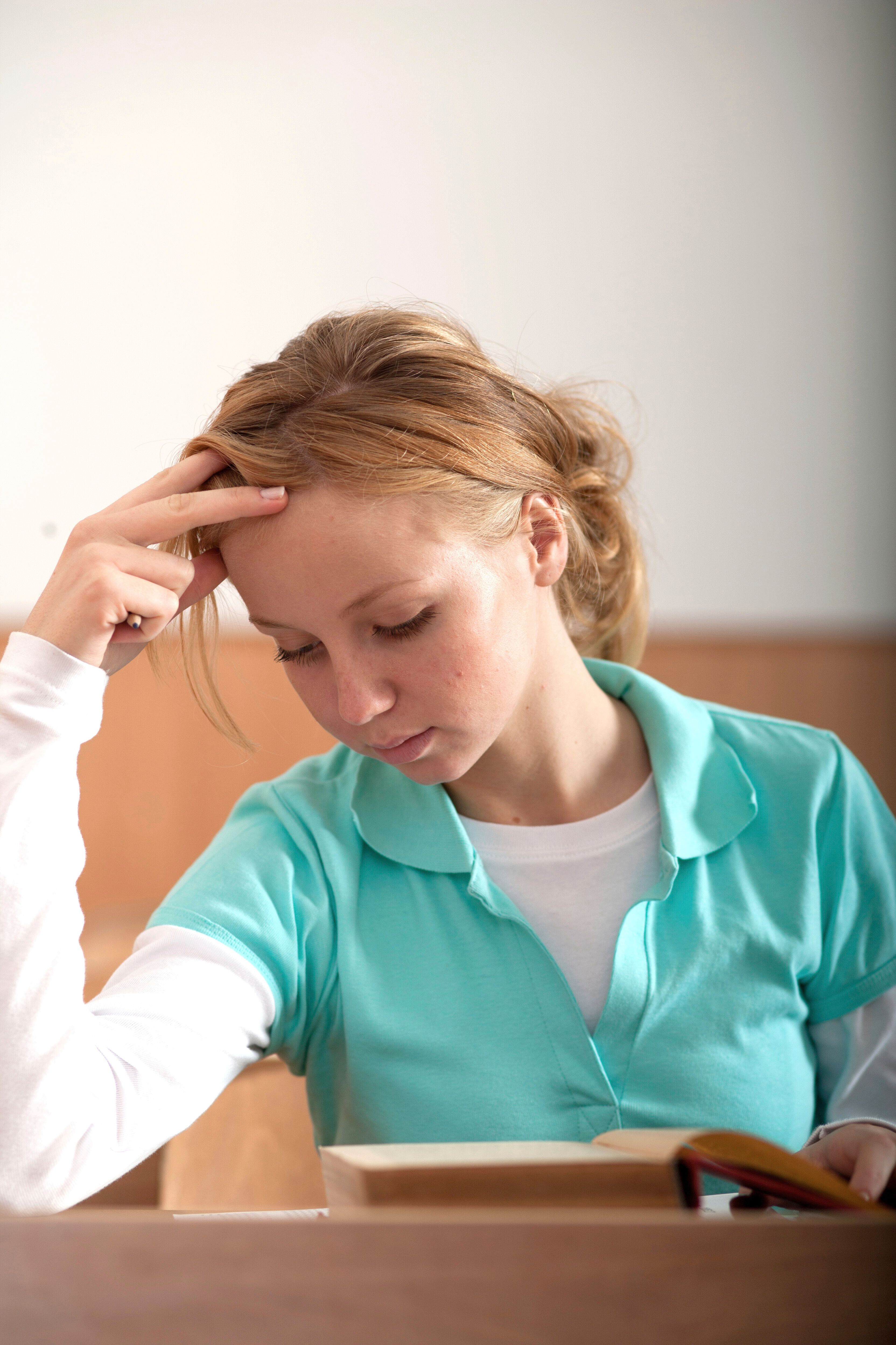 Portrait of a young woman reading in a casual setting, lost in thought.