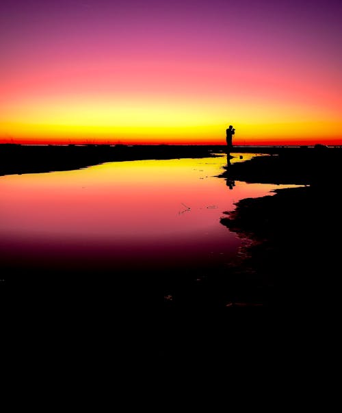 Silhouette of Photographer Standing on Shore during Sunset