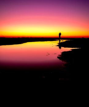 Silhouette of a photographer capturing a vibrant sunset along the seashore in Albania.