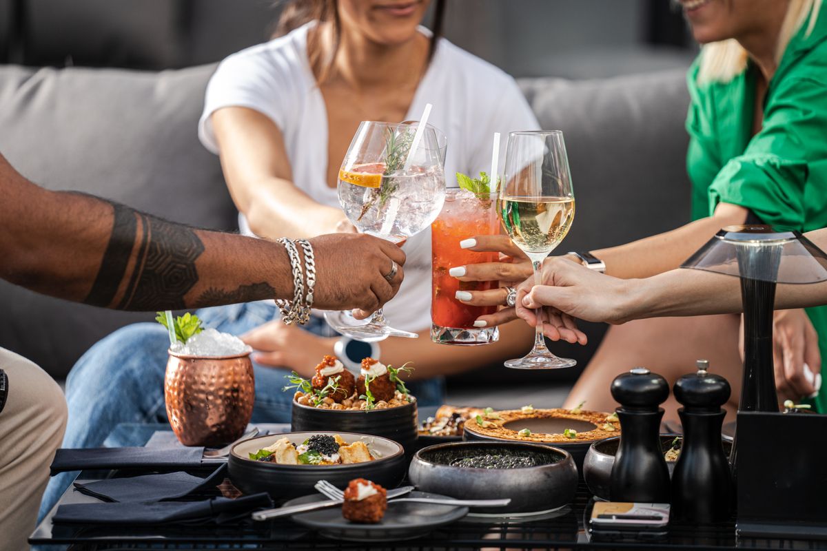 Groupe d’amis buvant des cocktails sur une terrasse en soirée