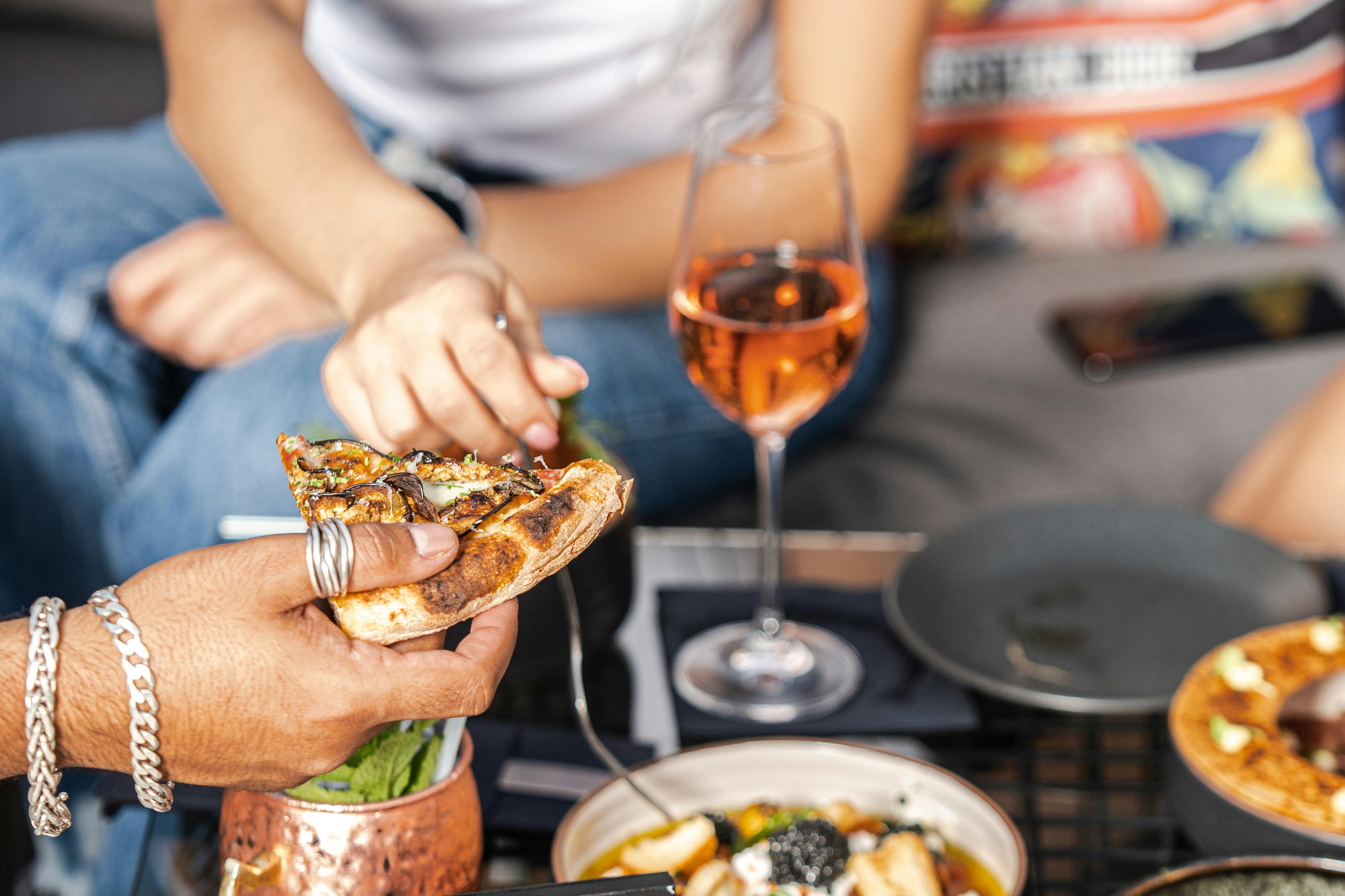 Friends enjoying pizza and rose wine at an indoor restaurant in Dubai, capturing a casual dining moment.