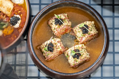 Free Exquisite crispy beef topped with caviar served in a savory broth, photographed in a Dubai restaurant. Stock Photo