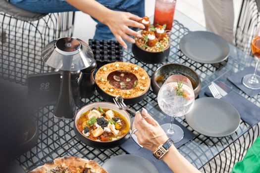Aerial view of Mediterranean dishes and drinks on a modern outdoor table setting.