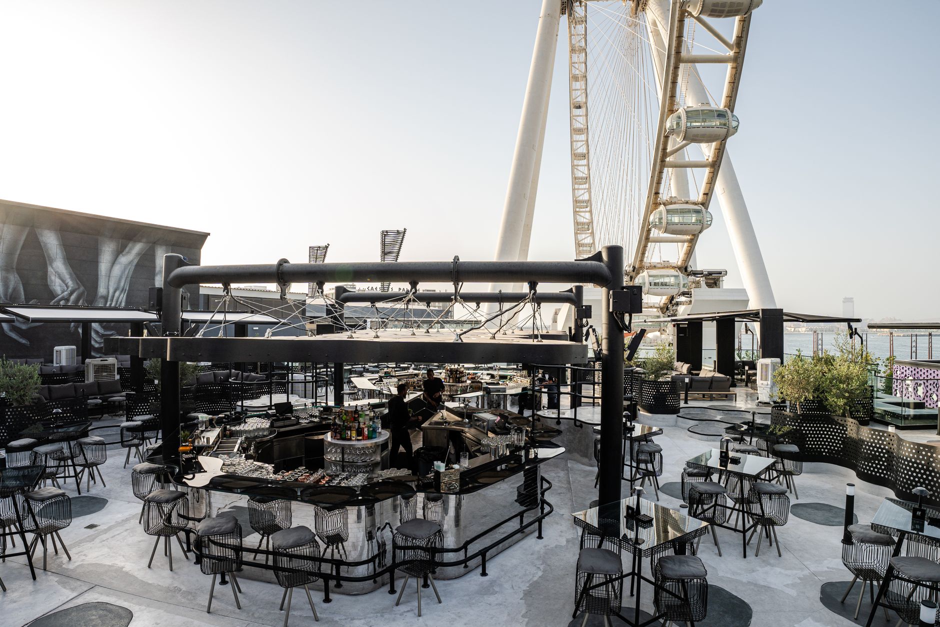 Modern rooftop bar in Dubai with a stunning view of a giant Ferris wheel.