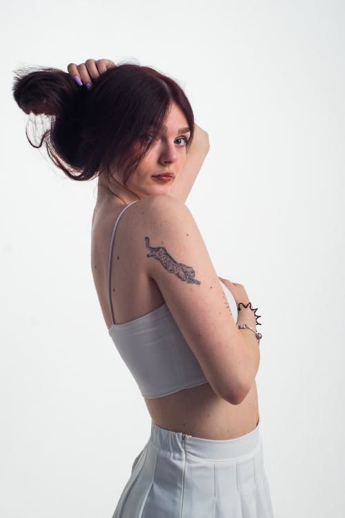 Woman with Tattoo on Arm Posing and Holding Her Hair