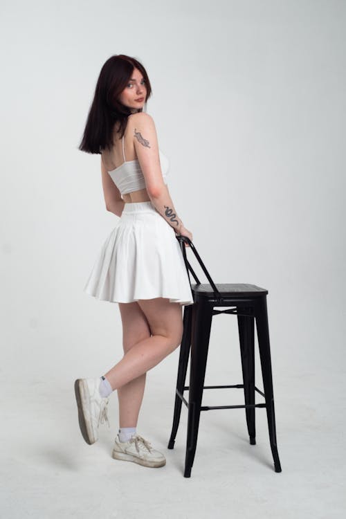 Woman in White Skirt Posing with Black Chair