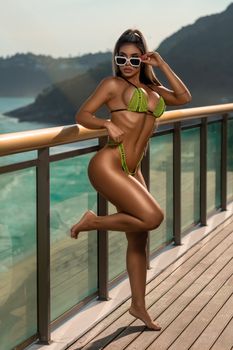 A fashionable woman posing in a vibrant bikini on a scenic balcony in Brazil.