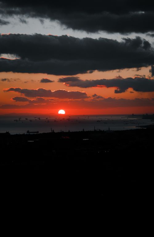 Free Stunning sunset over the ocean with silhouetted boats creates a dramatic sky and sea landscape. Stock Photo