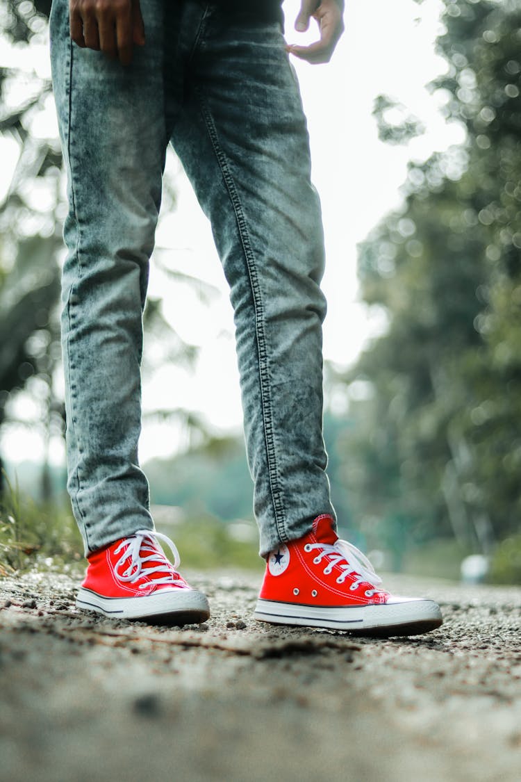 Close-up Of A Person Wearing Red Converse Shoes