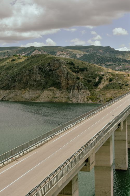 Free Breathtaking aerial shot of a bridge over a lush river with rolling hills. Stock Photo