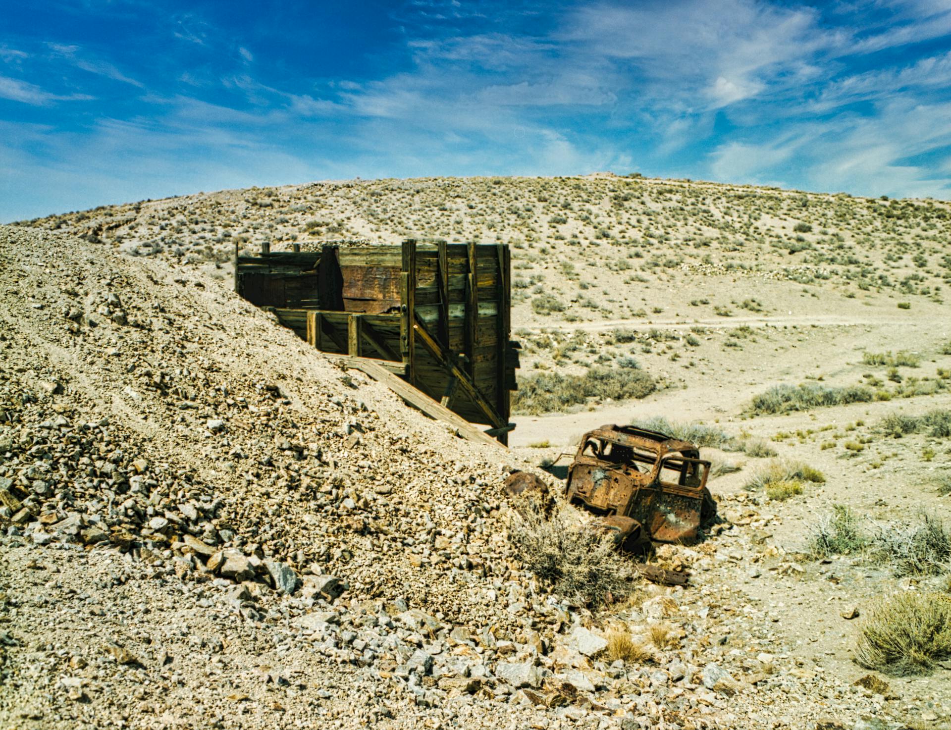 Explore the barren landscape of a deserted mine in Nevada, featuring a rusty vehicle.