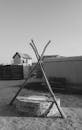 Grayscale Photo of Tied Sticks Over a Covered Water Well