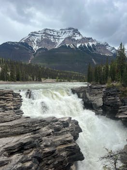 Breathtaking view of a waterfall against the snow-capped Canadian Rockies.