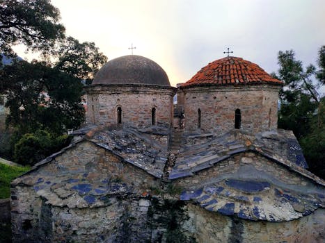A historic weathered Orthodox church with domes, captured at sunrise in Greece.