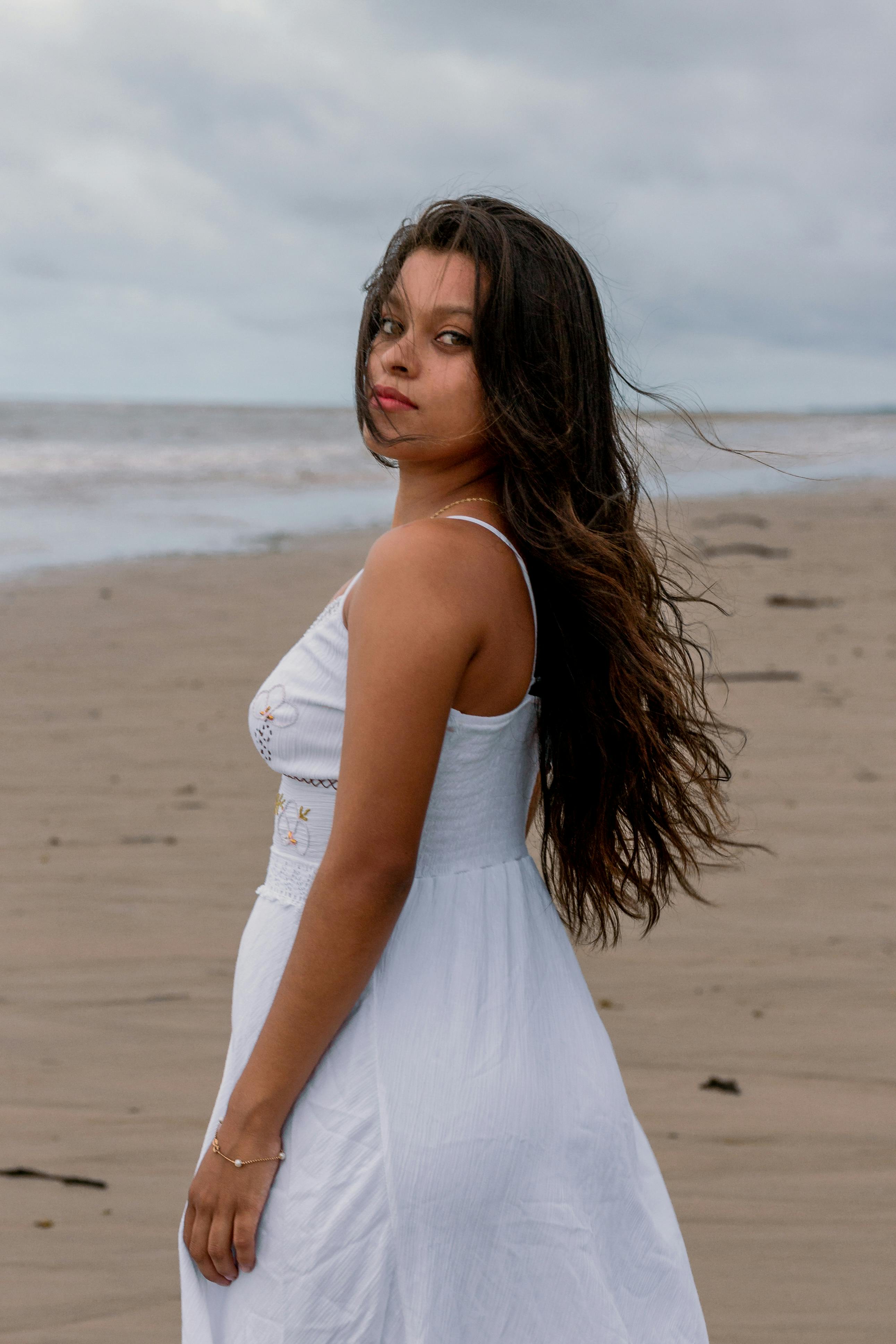 Woman in a white dress with long hair standing on a beach in Maranhão, Brazil.
