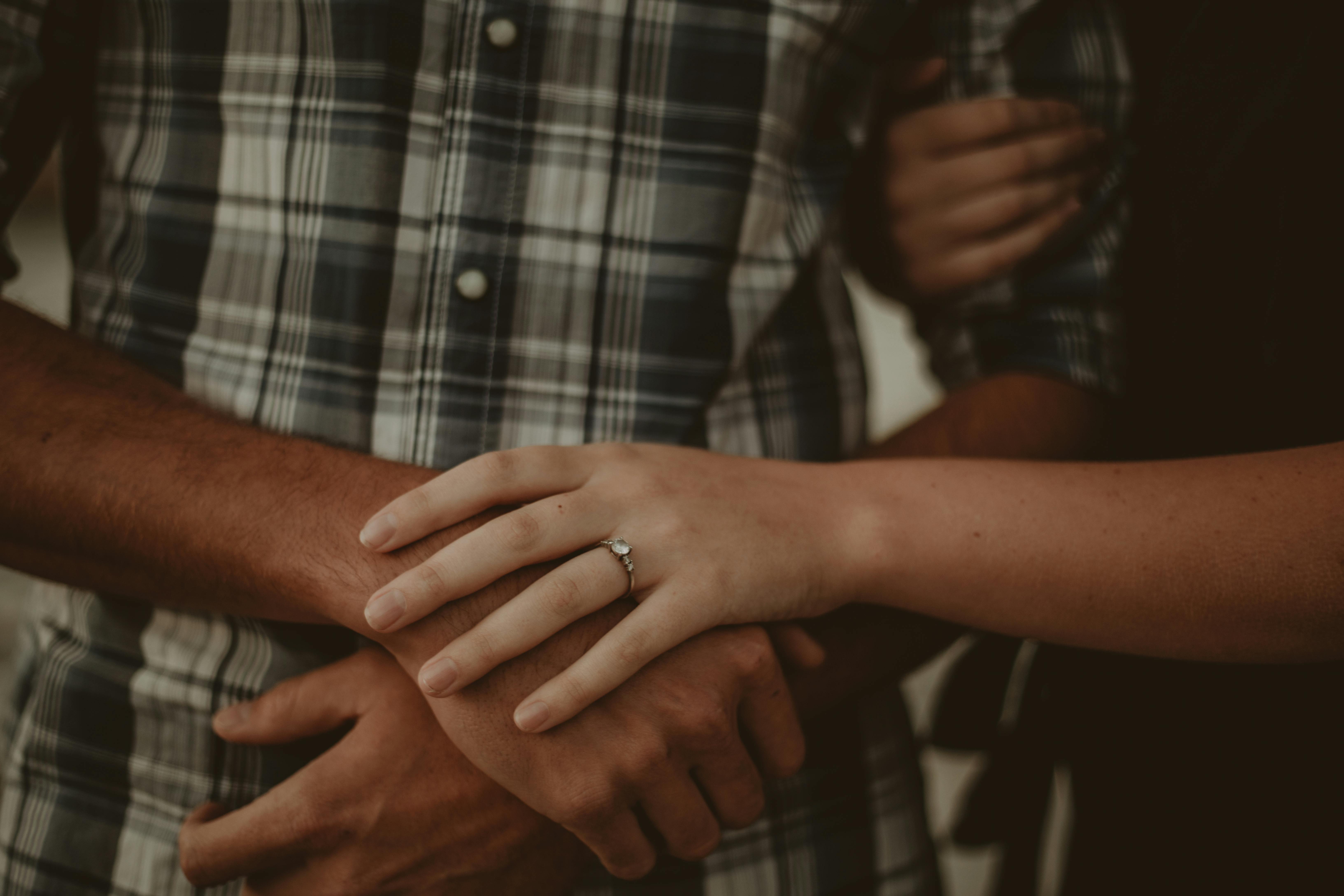 Close-up of a couple embracing, featuring an engagement ring, symbolizing love.