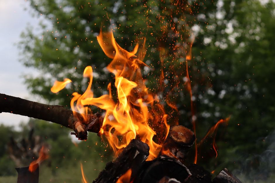 A lively campfire burning with vivid flames against a natural backdrop in the evening.