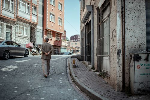 Free A man walks down a cobblestone street in a city neighborhood. The scene captures urban architecture. Stock Photo