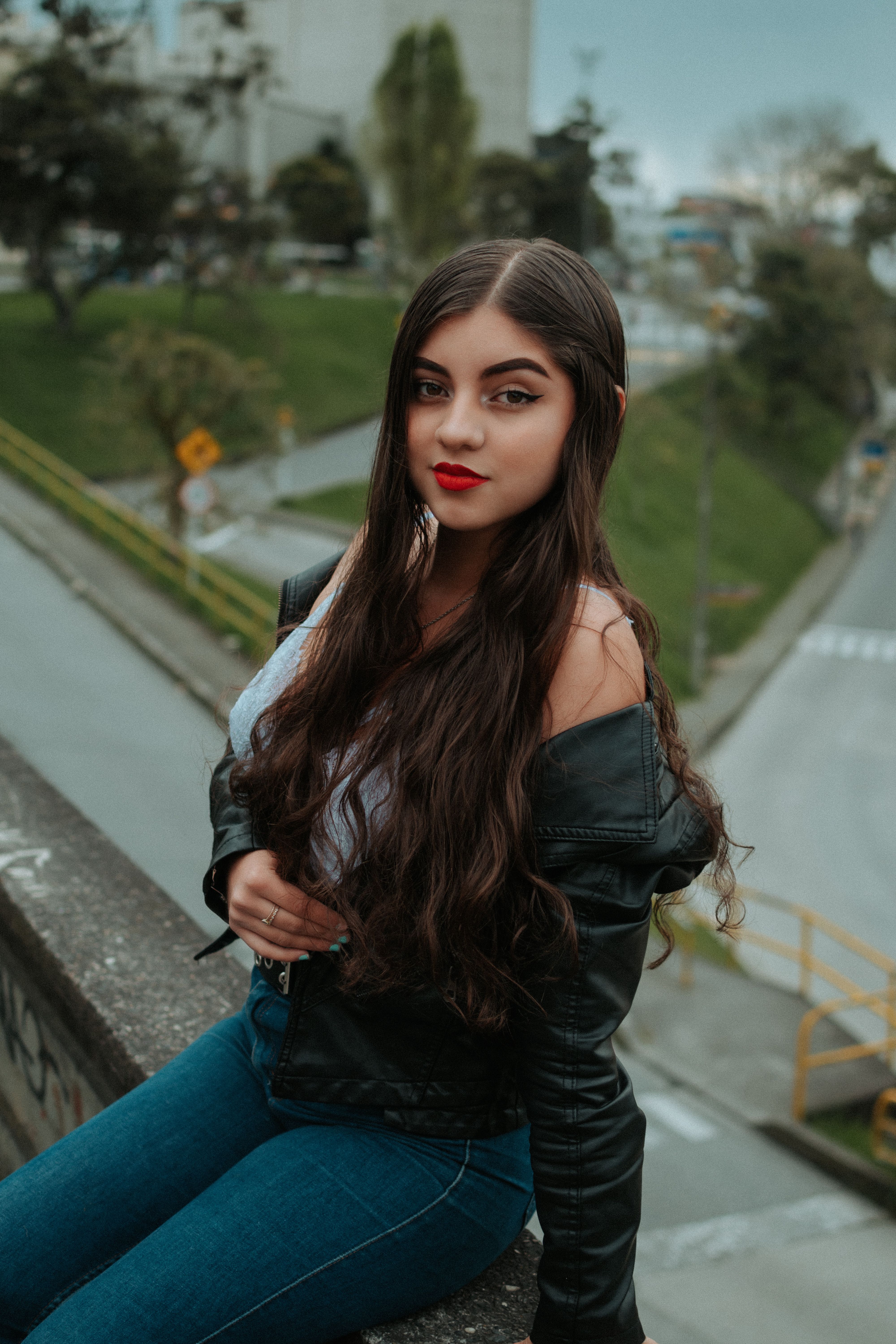 Woman in leather jacket with off-shoulder top and wide-leg jeans
