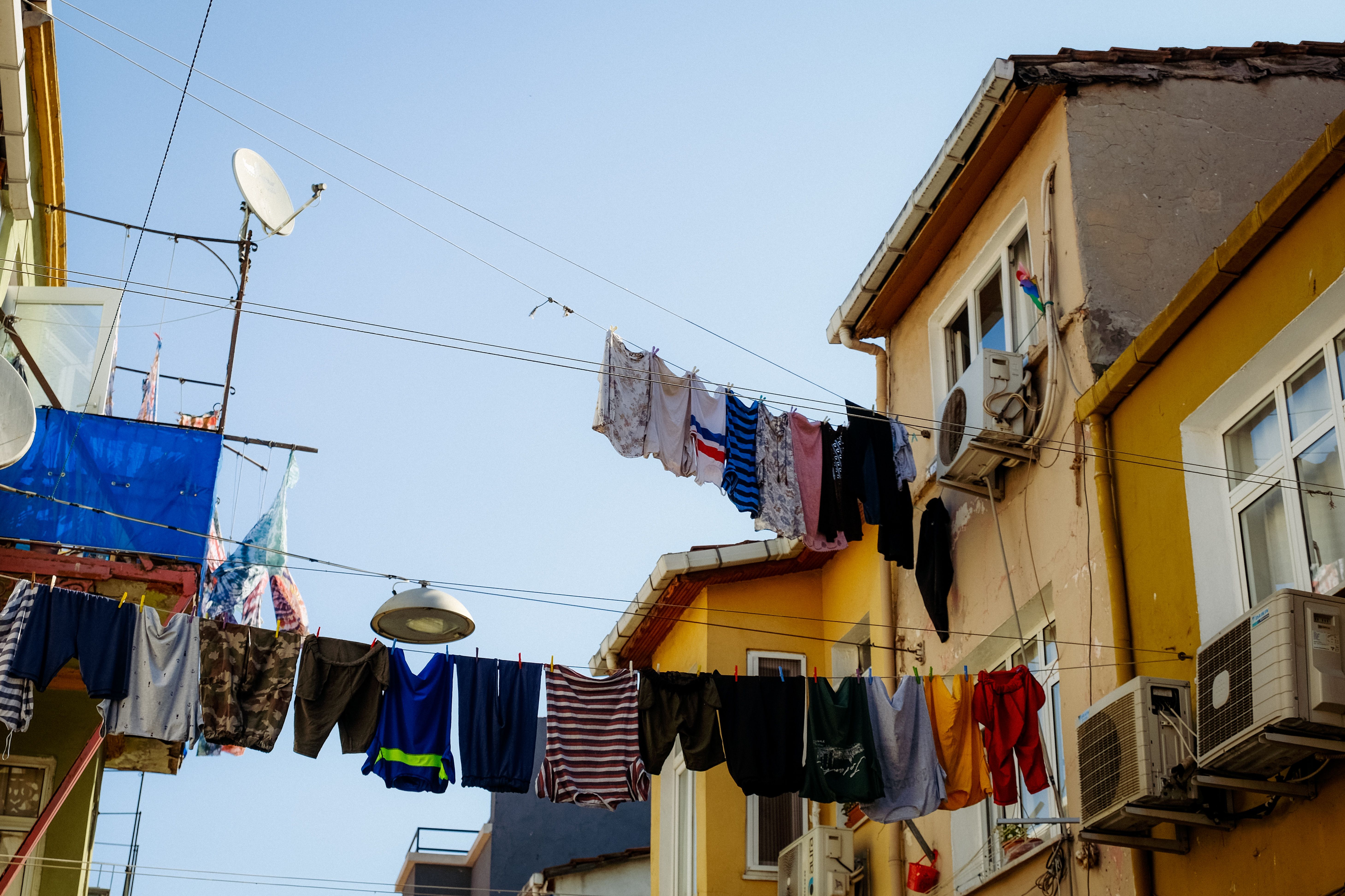 Vibrant clothes hanging on clotheslines between buildings in a sunny urban neighborhood.