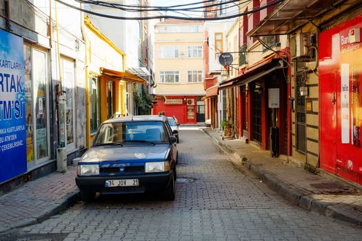 Colorful alleyway with parked car in urban setting, featuring vibrant facades and signage.