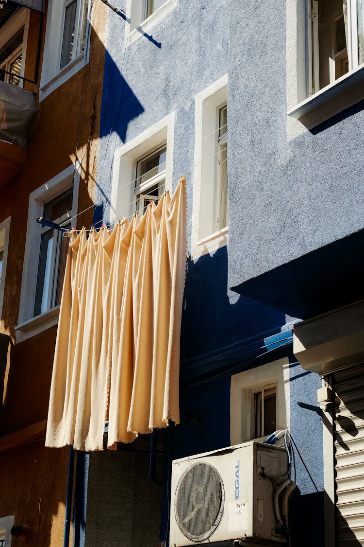 A Beige Curtain Hanging Outside Glass Windows Of A Building