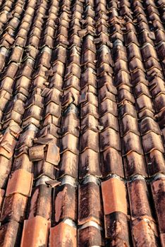 Close-up view of a weathered clay tiled rooftop showcasing unique textures and aging patterns.