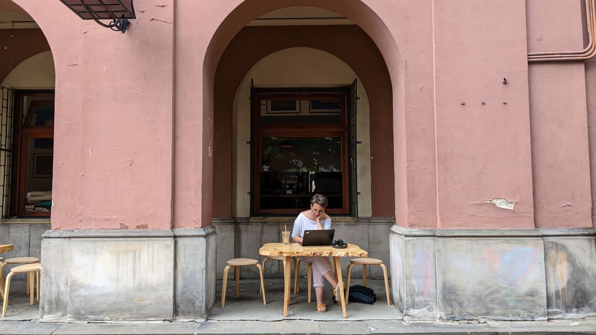 Woman working on a laptop outside a cafe in Warsaw, Poland. Relaxing, urban vibe.