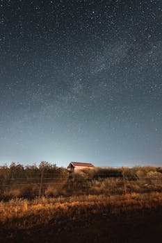 A serene view of a rural house beneath a vast starry night sky, showcasing natural beauty.