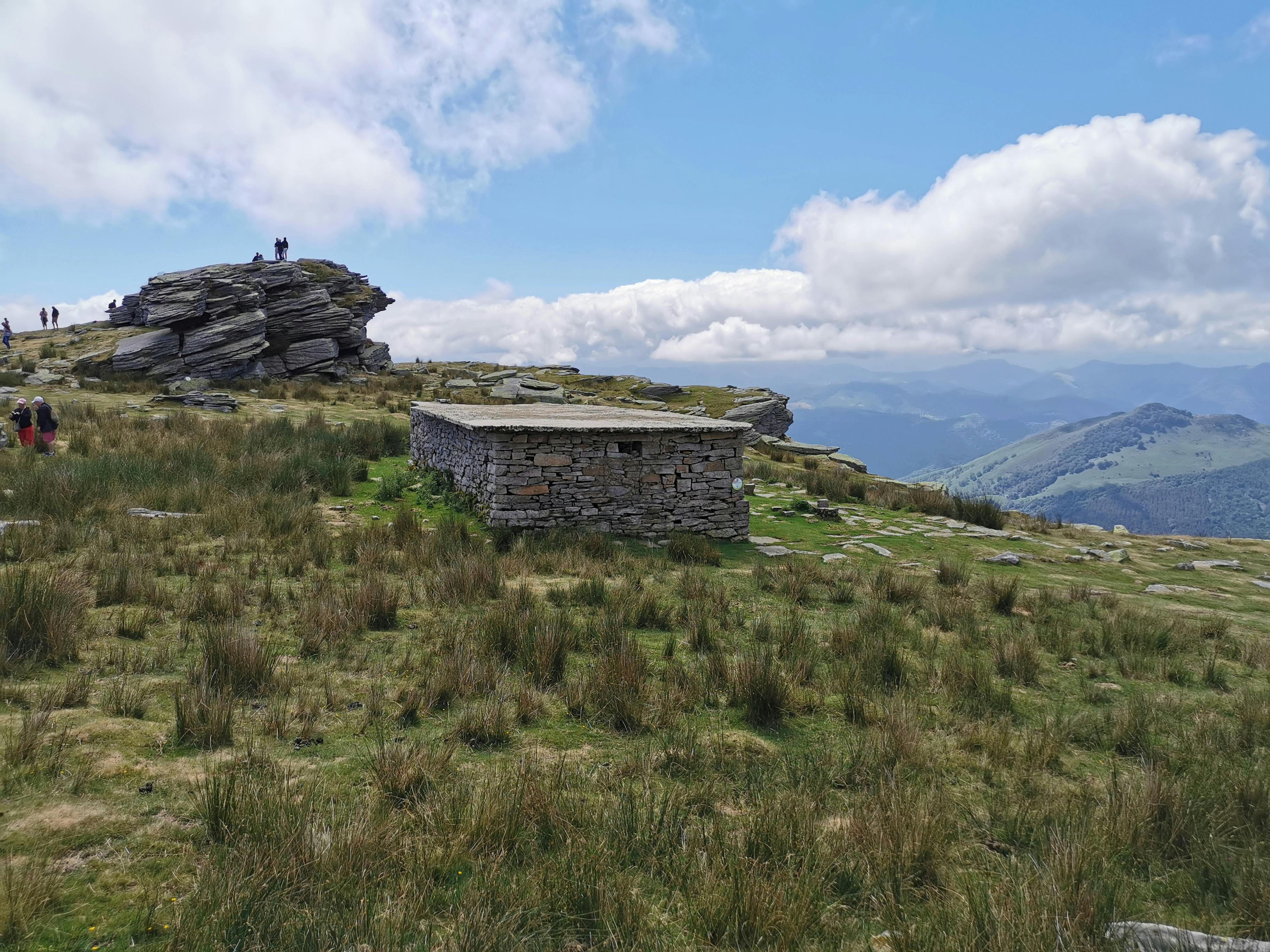 Explore the lush hills of Ascain, France with a rustic stone shelter.