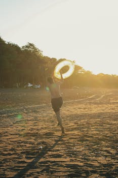 A joyful man runs along a sandy beach with a swim ring during sunset, enjoying a summer day.